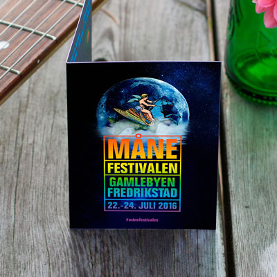 Bildet viser miniprogrammet til Månefestivalen 2016, på et bord med deler av en ølflaske og en gitar synlig.