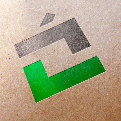 Bildet viser logoen til Villatjenesten (illustrerer et sort hus med pipe, og en grønn avkrysningshake under) trykket på grovt papir med tekstur.